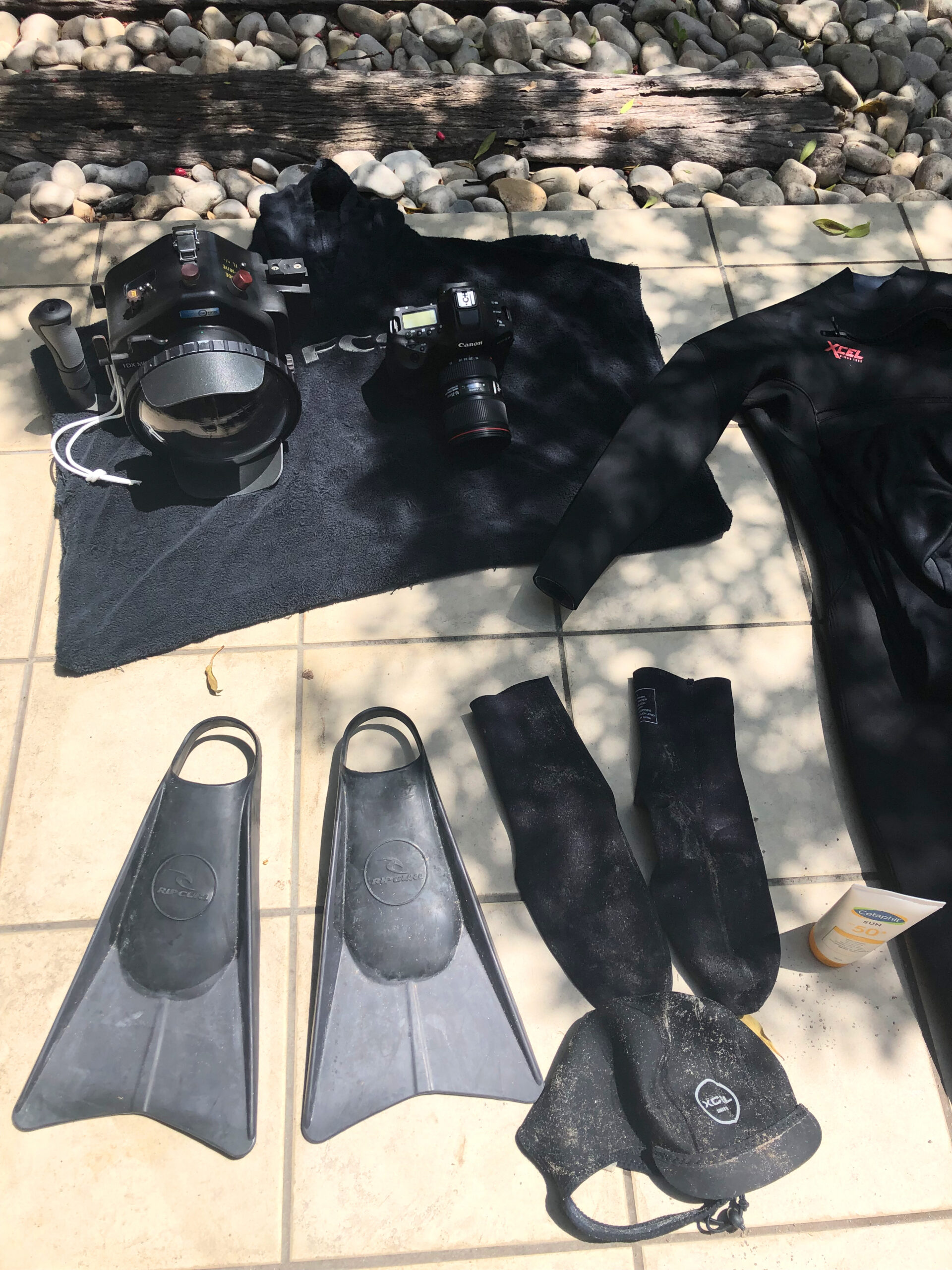 Pro-level surf surfing and ocean photographer gear: full wetsuit, swim fins, high-end-underwater camera underwater housing for extended outdoor shoots in dynamic ocean conditions